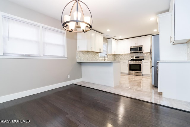 kitchen featuring an inviting chandelier, tasteful backsplash, appliances with stainless steel finishes, and light wood-type flooring