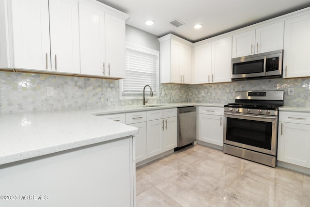 kitchen featuring visible vents, backsplash, appliances with stainless steel finishes, white cabinets, and a sink