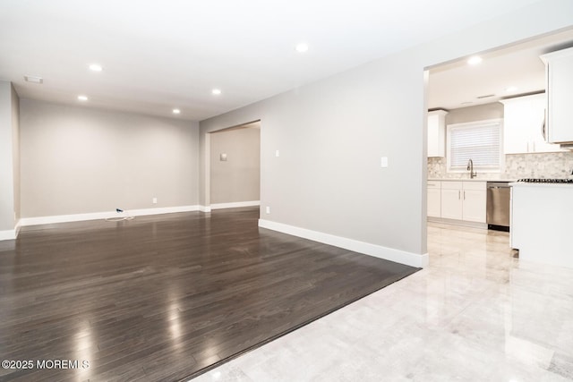 unfurnished living room featuring recessed lighting, baseboards, light wood-style flooring, and a sink