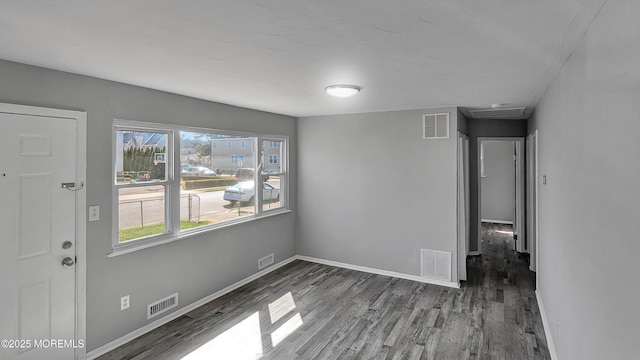 unfurnished dining area with wood finished floors, visible vents, and baseboards