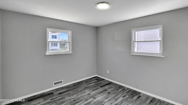 unfurnished room featuring visible vents, baseboards, and dark wood finished floors