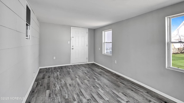 empty room featuring a wealth of natural light, baseboards, and wood finished floors