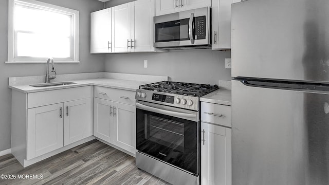 kitchen featuring light countertops, white cabinets, appliances with stainless steel finishes, and a sink