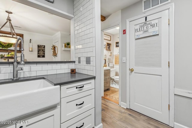 144 Brandywine Ct Unit 332, Brick, NJ 08724 - kitchen with dark countertops, decorative backsplash, light wood-style floors, white cabinetry, and a sink