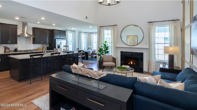 living room featuring a fireplace with flush hearth, recessed lighting, and light wood finished floors