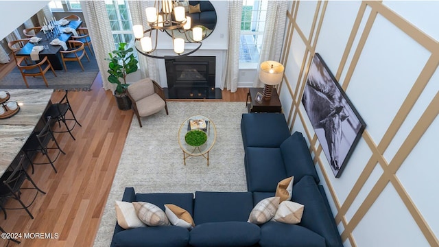 living area featuring a glass covered fireplace, a notable chandelier, and wood finished floors