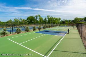 view of tennis court featuring community basketball court and fence