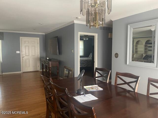 dining space featuring ceiling fan with notable chandelier, crown molding, wood finished floors, and baseboards