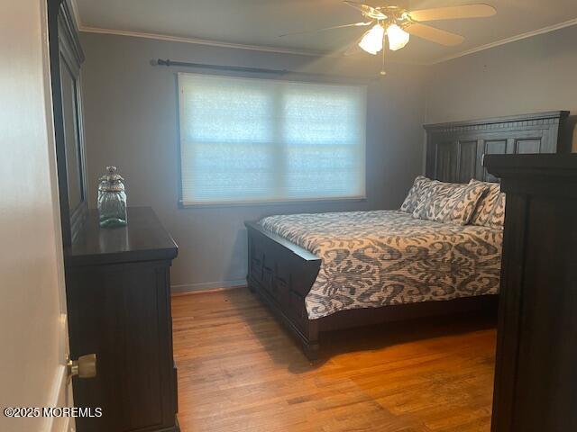 bedroom featuring ceiling fan, baseboards, light wood-type flooring, and ornamental molding