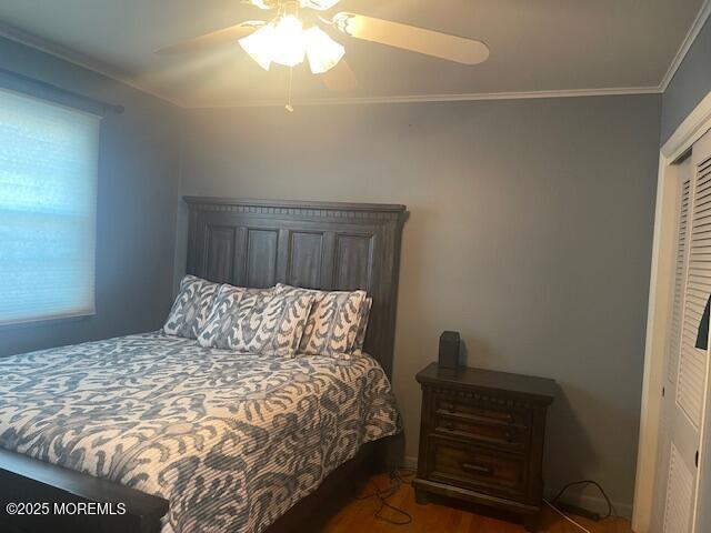 bedroom with a closet, crown molding, a ceiling fan, and wood finished floors