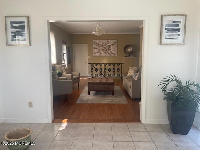 living area with light tile patterned floors, baseboards, and crown molding