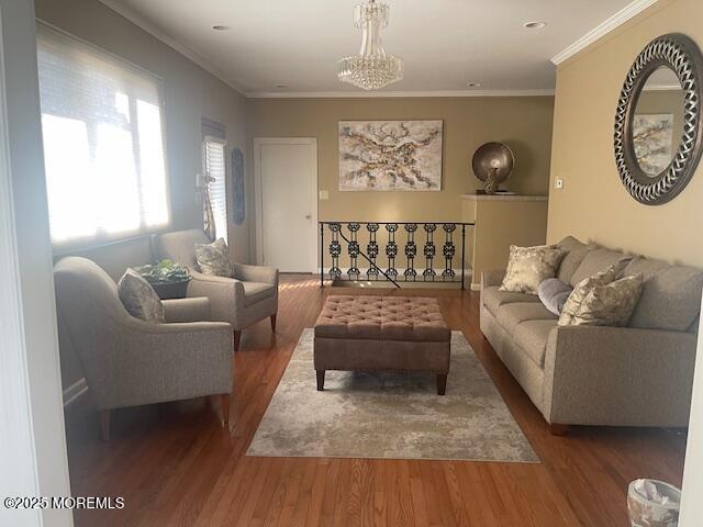 living area featuring an inviting chandelier, wood finished floors, and crown molding