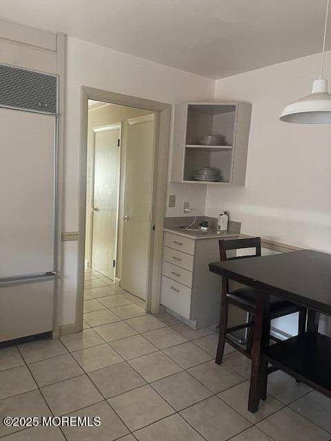 kitchen featuring light tile patterned floors, open shelves, stainless steel built in fridge, light countertops, and white cabinetry