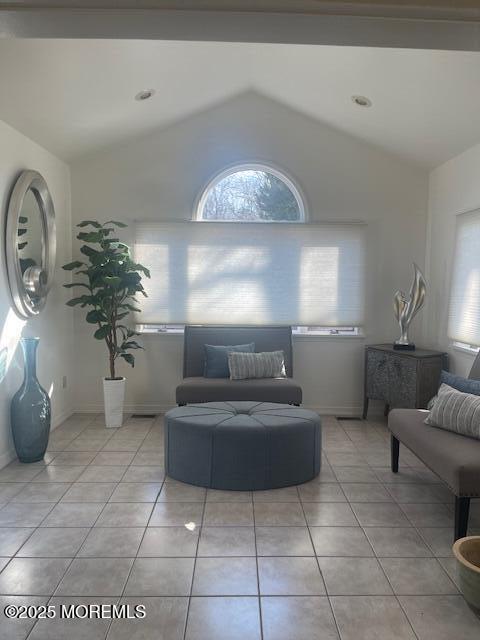 living room with vaulted ceiling, light tile patterned floors, and baseboards