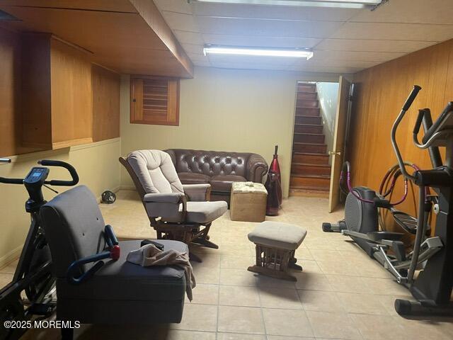 workout area featuring light tile patterned floors, a paneled ceiling, and wood walls