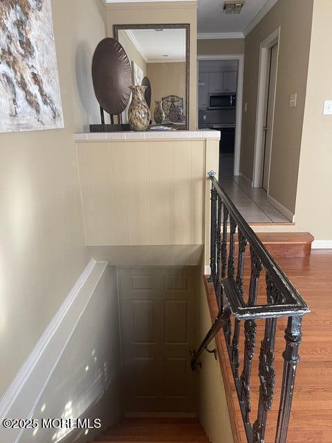 stairs featuring visible vents, crown molding, and wood finished floors