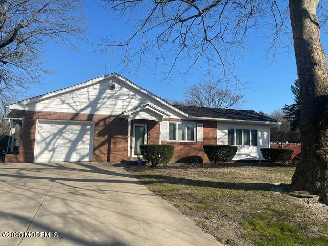 ranch-style home with a garage, brick siding, concrete driveway, and a front yard