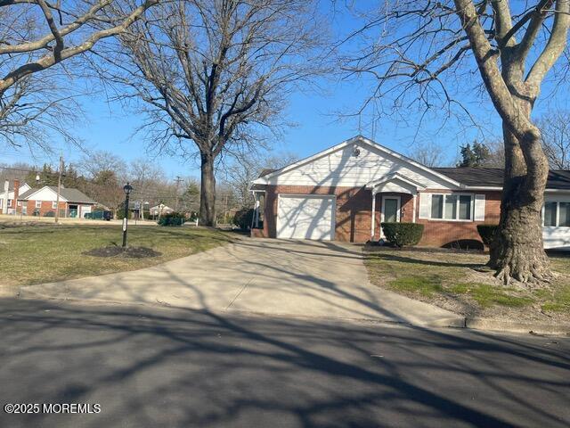 view of front of house with brick siding, driveway, a front yard, and a garage