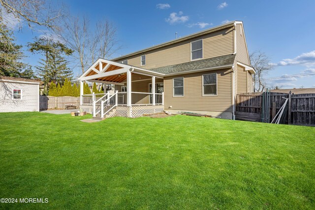 back of property featuring a fenced backyard, a lawn, an outdoor structure, and roof with shingles