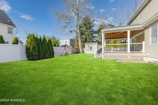 view of yard with ceiling fan, a shed, covered porch, a fenced backyard, and an outdoor structure