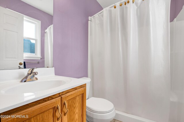 bathroom featuring a shower with curtain, toilet, and vanity