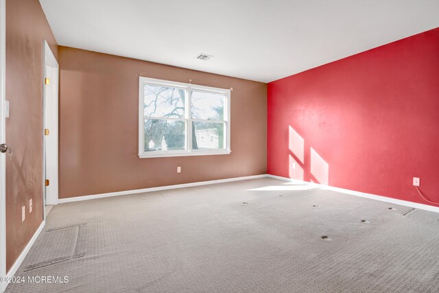 carpeted spare room with visible vents and baseboards