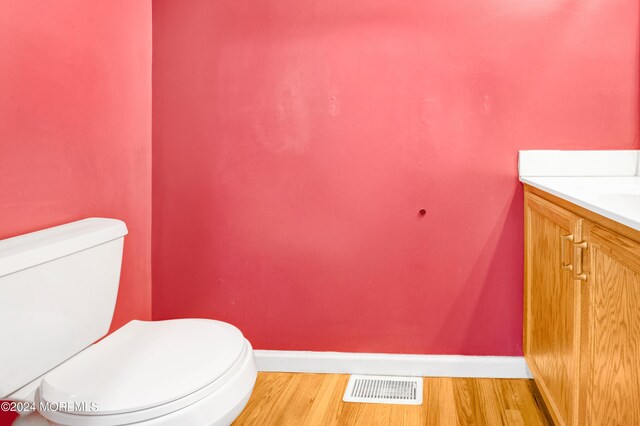 bathroom featuring visible vents, toilet, wood finished floors, baseboards, and vanity