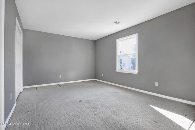 carpeted spare room featuring visible vents and baseboards