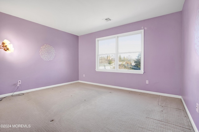 carpeted empty room featuring baseboards and visible vents