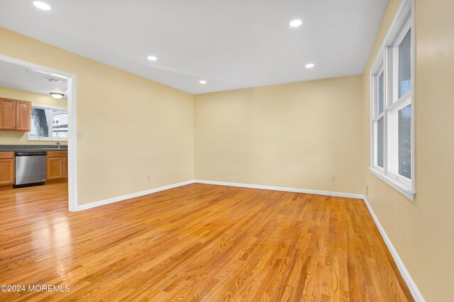 spare room with recessed lighting, baseboards, a sink, and light wood finished floors