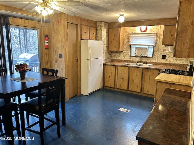 kitchen with visible vents, freestanding refrigerator, ceiling fan, a sink, and brown cabinets