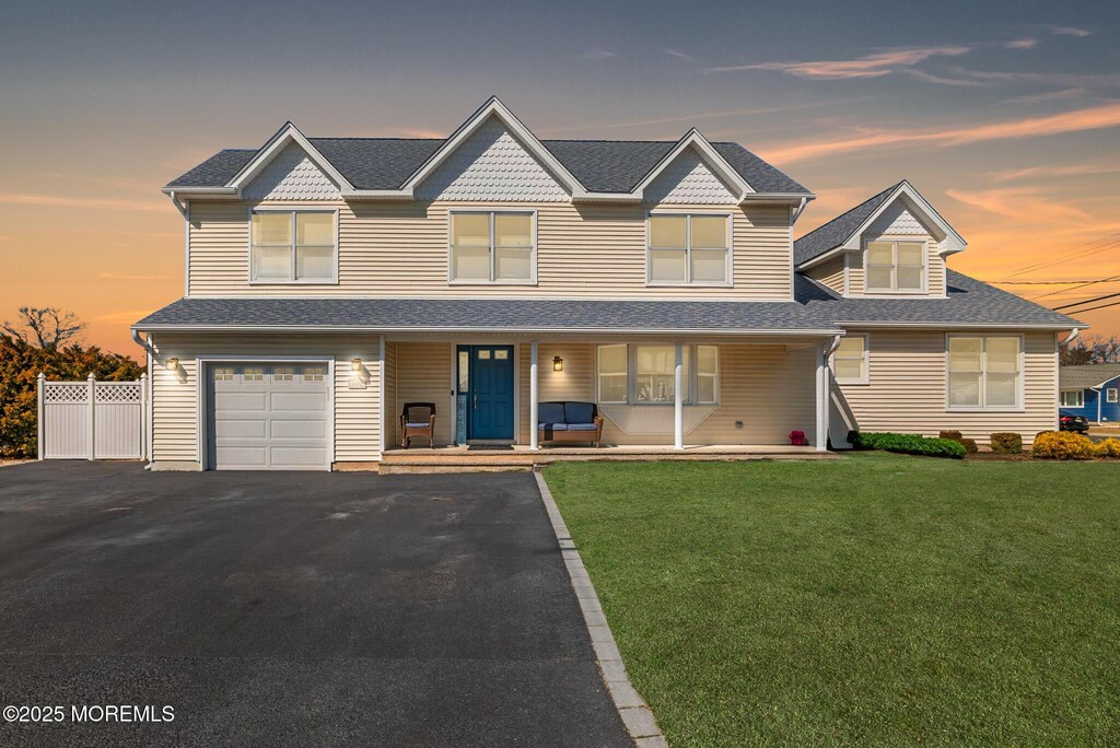 1401 Rue Mirador Pt, Pleasant, NJ 08742 - traditional home featuring aphalt driveway, covered porch, fence, a front yard, and a garage