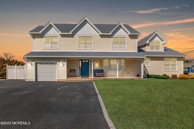 view of front facade with fence, a porch, an attached garage, a front lawn, and aphalt driveway