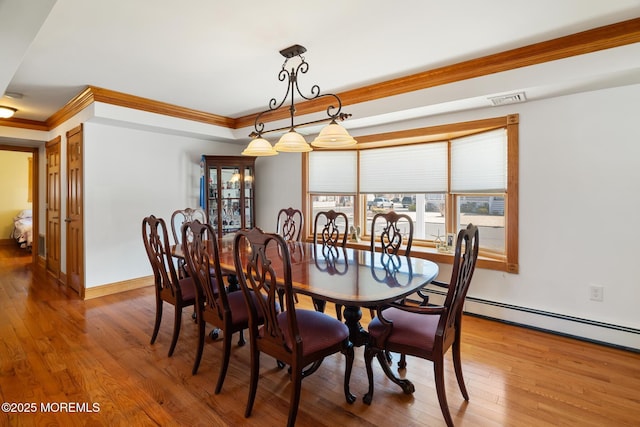 dining room with hardwood / wood-style flooring, crown molding, visible vents, and baseboards