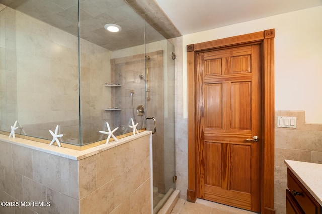 full bathroom featuring tile patterned flooring, a stall shower, tile walls, and vanity