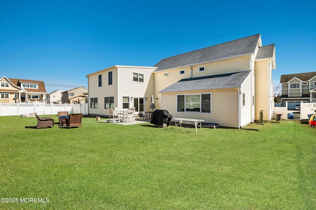 rear view of house featuring a patio area, a lawn, a shingled roof, and fence