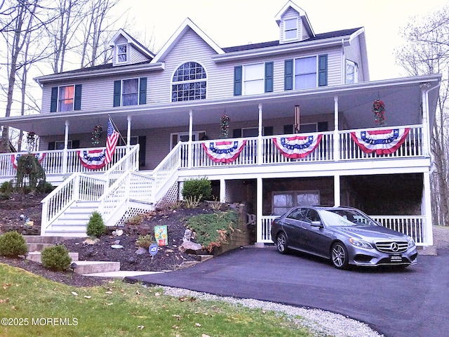 view of front of house with aphalt driveway, covered porch, and stairs