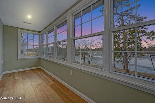 unfurnished sunroom featuring hardwood / wood-style flooring, baseboards, and visible vents
