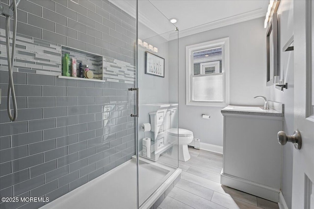 full bathroom with crown molding, baseboards, toilet, a tile shower, and vanity