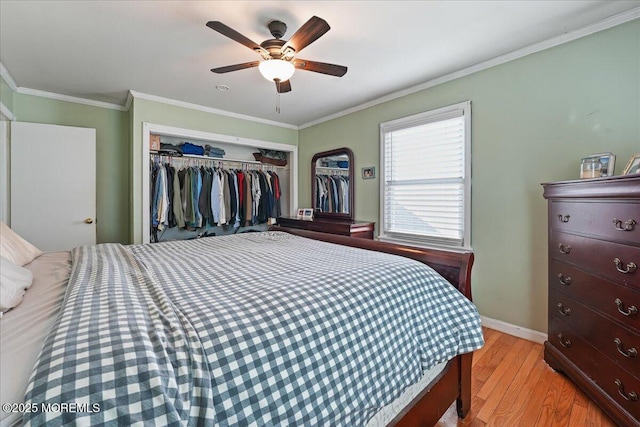 bedroom featuring baseboards, ornamental molding, wood finished floors, a closet, and a ceiling fan