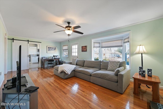 living room with crown molding, a barn door, light wood finished floors, and ceiling fan