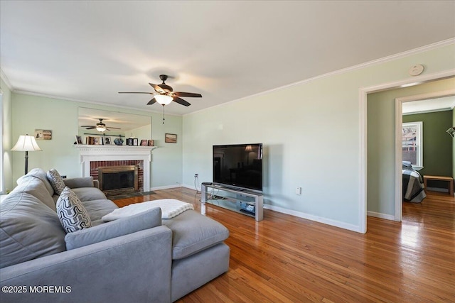 living area featuring ornamental molding, baseboards, a ceiling fan, and wood finished floors