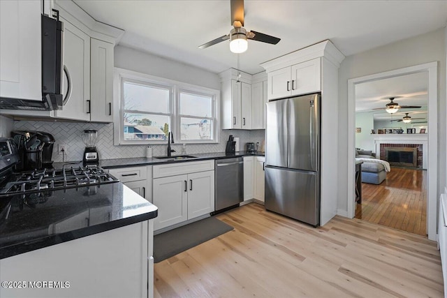 kitchen featuring a sink, light wood-type flooring, appliances with stainless steel finishes, and a ceiling fan