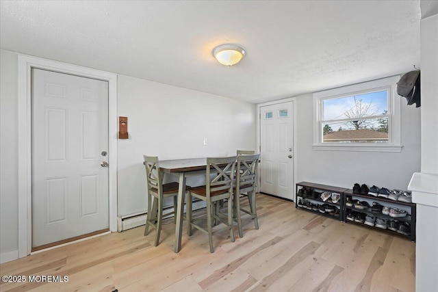 dining room with light wood-type flooring and a textured ceiling