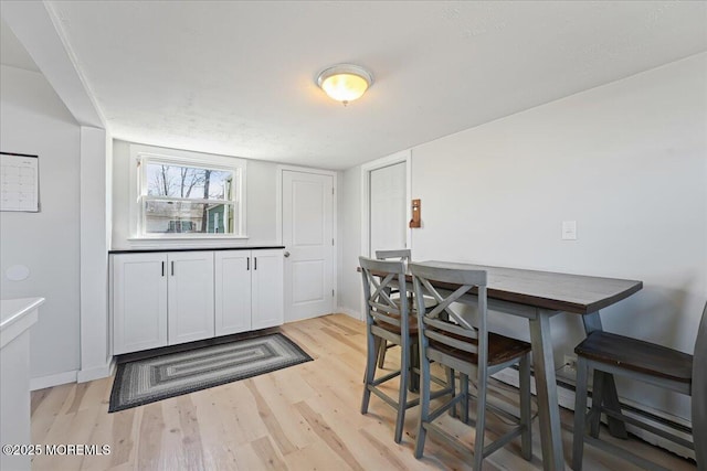 dining area featuring baseboards and light wood-style floors