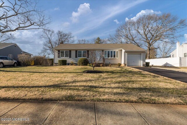 ranch-style home featuring fence, an attached garage, entry steps, a front lawn, and aphalt driveway