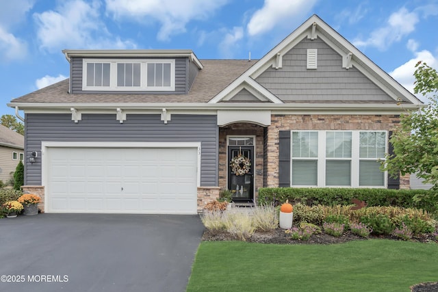 craftsman house with aphalt driveway, an attached garage, stone siding, and roof with shingles