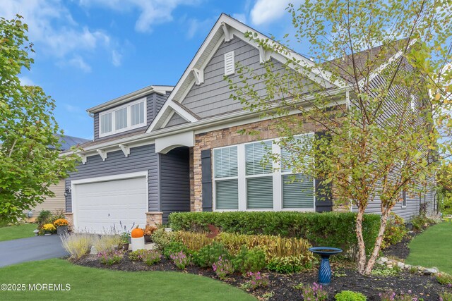 craftsman-style home with aphalt driveway, stone siding, and a garage