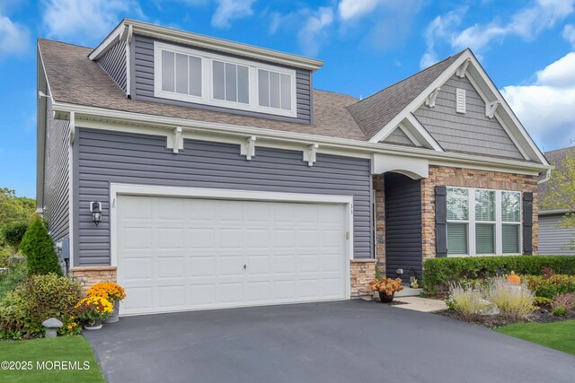 craftsman inspired home featuring a garage, stone siding, driveway, and a shingled roof