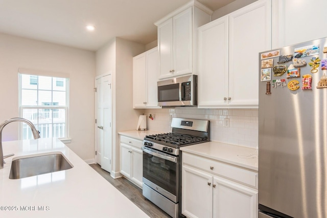 kitchen with a sink, stainless steel appliances, light countertops, white cabinetry, and tasteful backsplash